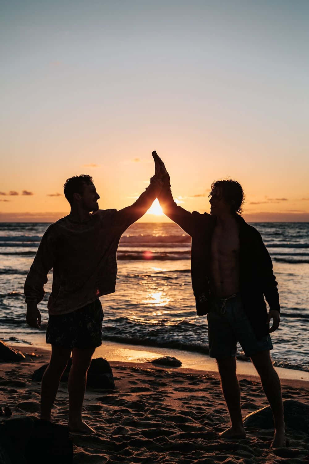 Bạn bè high five lúc hoàng hôn trên bãi biển Hình nền