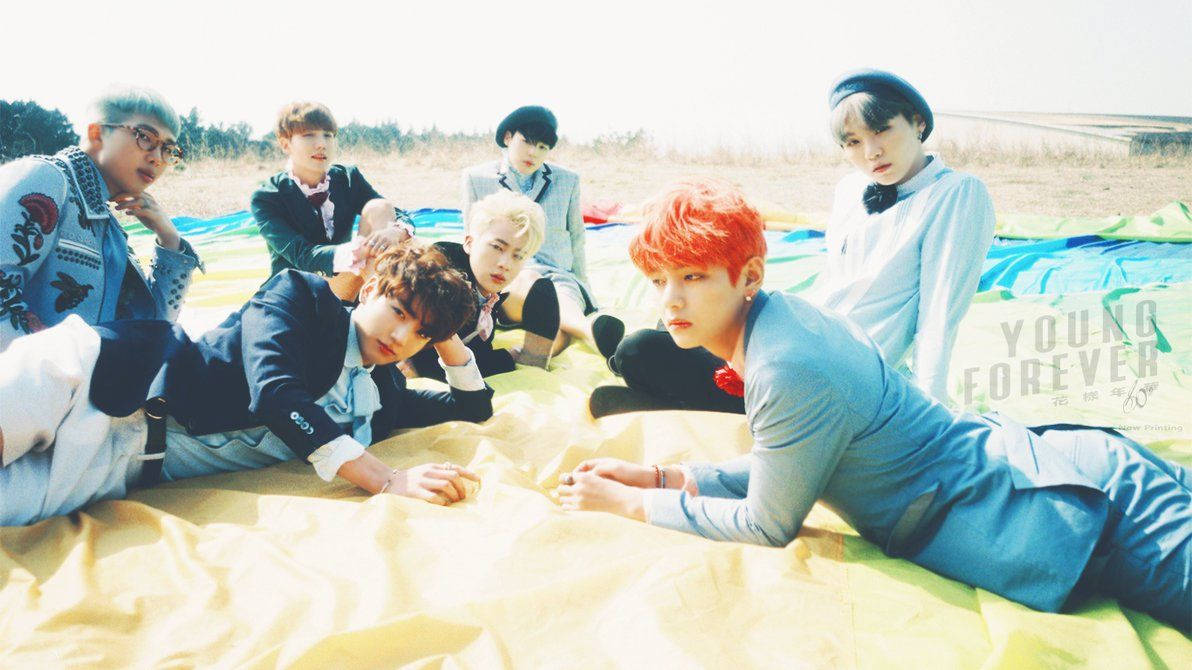 Các thành viên BTS nằm trên một tấm khăn trên bãi biển vào mùa Hè.