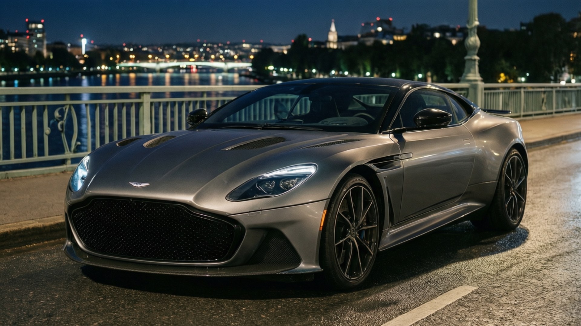 Aston Martin DBS Superleggera trên cây cầu vào ban đêm với ánh đèn thành phố.