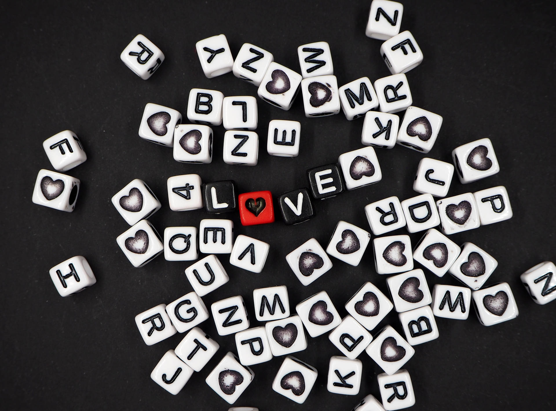 Những viên xúc xắc đen xếp thành chữ "love" với trái tim thay thế chữ "O" và các viên xúc xắc trắng rải rác trên nền đen dành cho Ngày lễ Tình nhân.