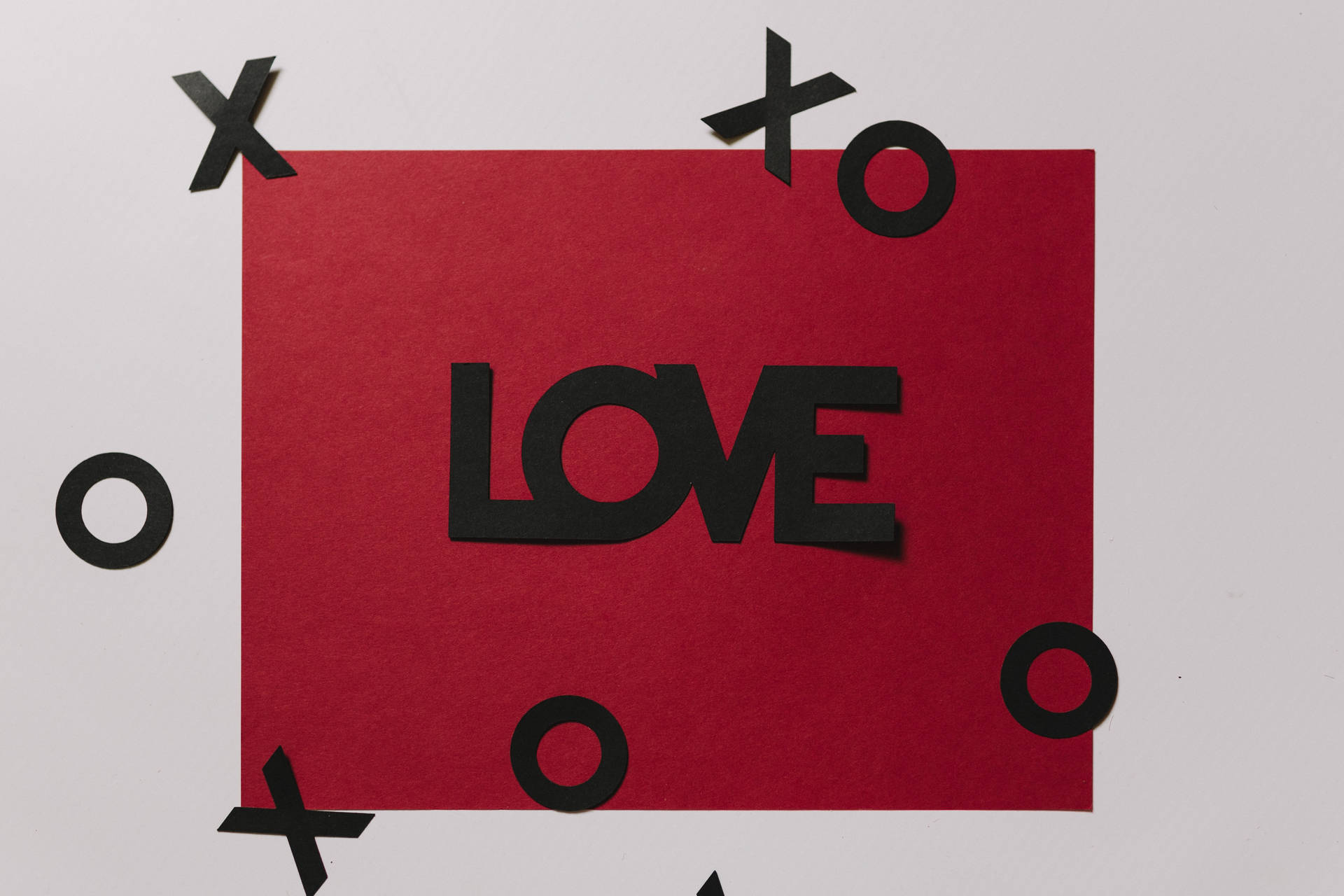 Bức thư tình màu đỏ có dòng chữ 'Love' màu đen và các hình cắt XOXO nổi trên nền trắng.