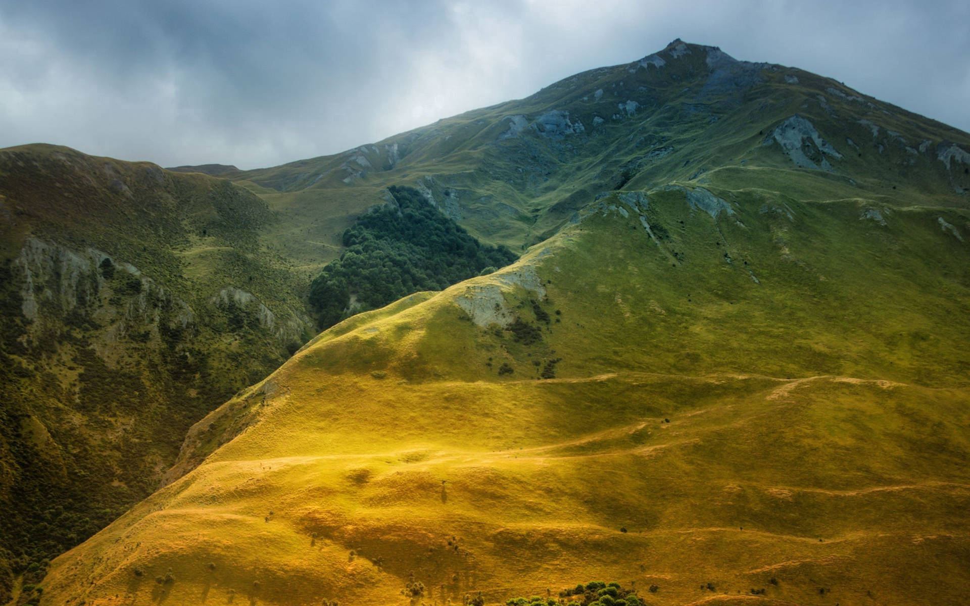 Núi trong xanh với mặt đất vàng xanh dưới bầu trời xám