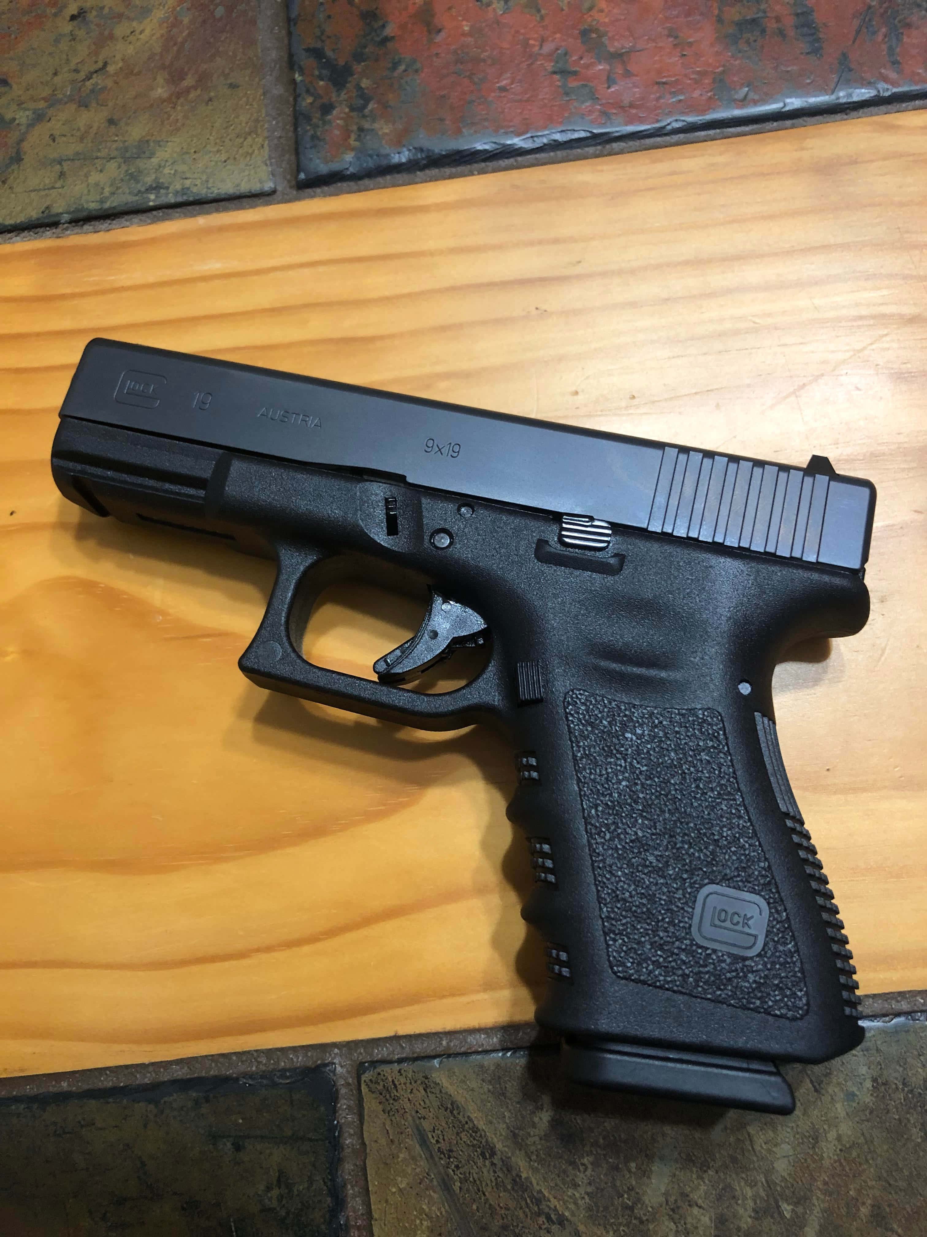 một khẩu súng lục Glock màu đen trên sàn gỗ Hình nền
