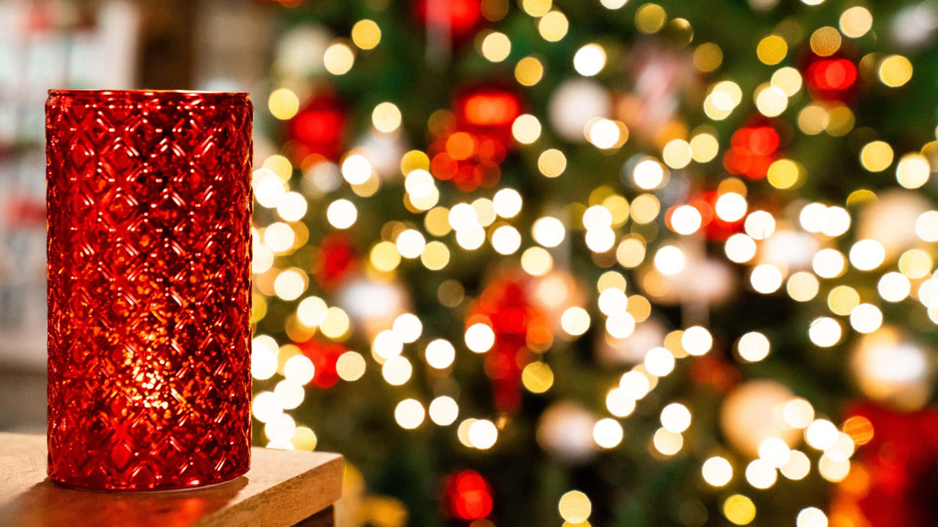 Một ngọn nến đỏ đặt trên bàn trước cây thông Noel Hình nền