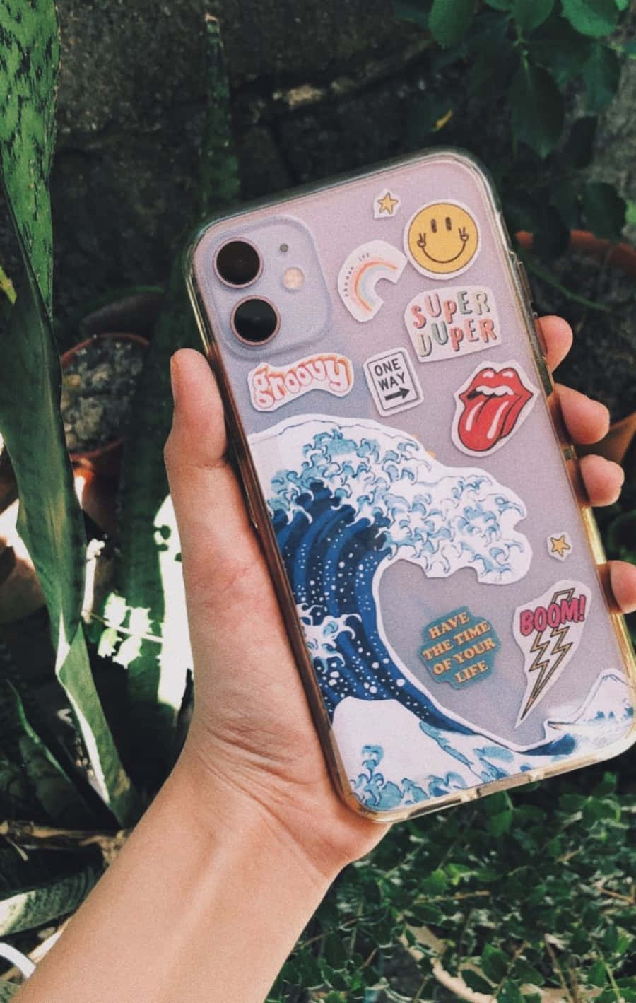 Một người cầm ốp lưng điện thoại có dán sticker Hình nền