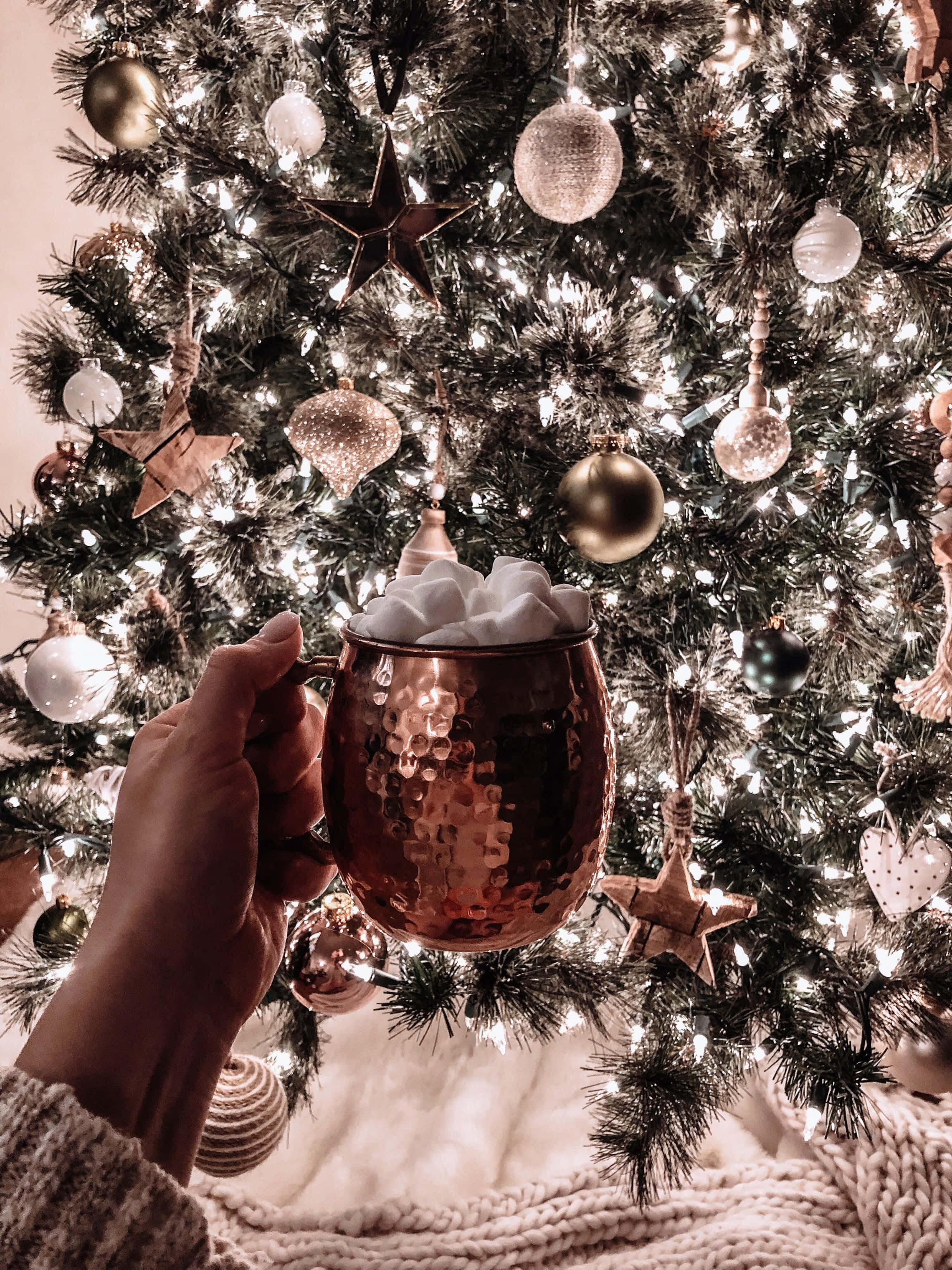 Một người cầm tách cà phê trước cây thông Noel Hình nền