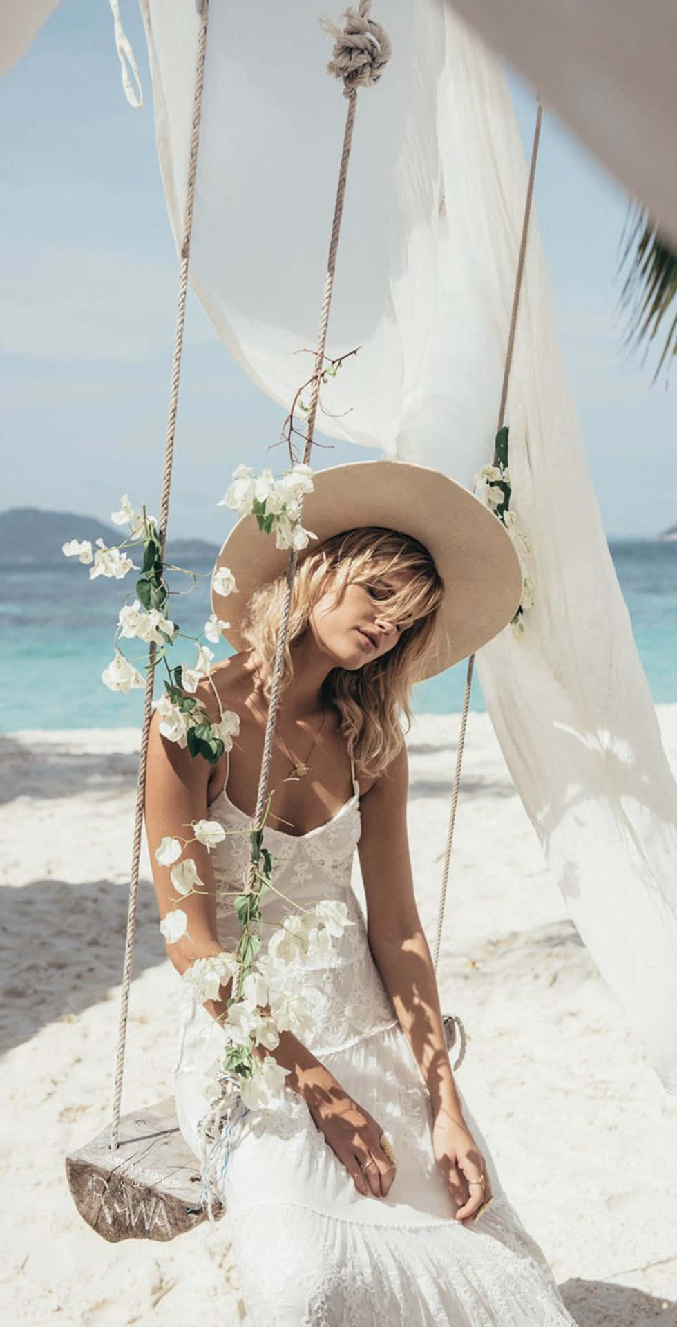 Một người phụ nữ mặc váy trắng ngồi trên xích đu trên bãi biển Hình nền