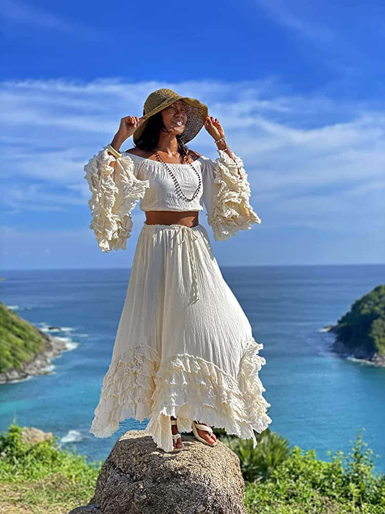 Một người phụ nữ mặc váy trắng đứng trên tảng đá Hình nền