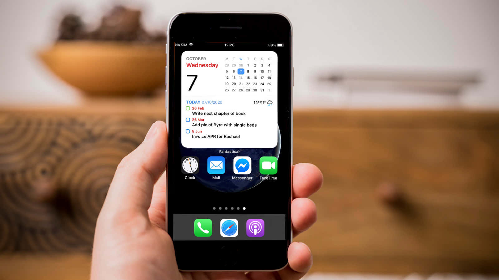 Người cầm iPhone có lịch trên màn hình Hình nền