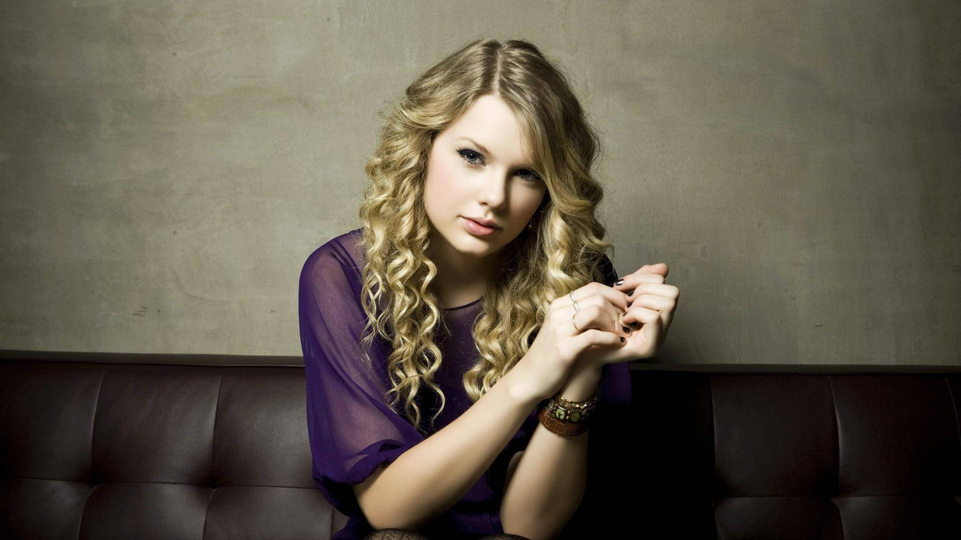 Hình nền Taylor Swift tóc xoăn ngồi trong áo lưới tím.