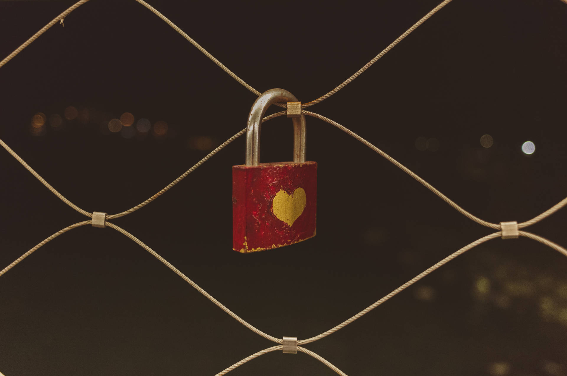 Ổ khóa sơn hình trái tim đỏ và vàng khóa trên hàng rào lưới. Ổ khóa tình yêu cổ điển dành cho các cặp đôi.