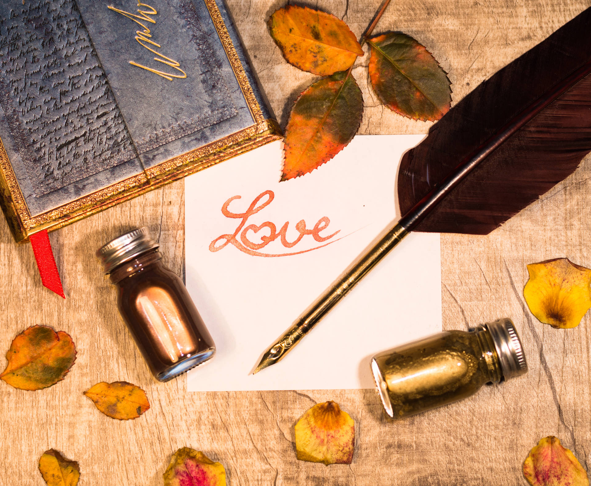 Dòng chữ "Love" màu cam viết trên mảnh giấy trắng với bút lông và lọ mực trên bàn gỗ. Thư tình dành cho Ngày lễ Tình nhân.