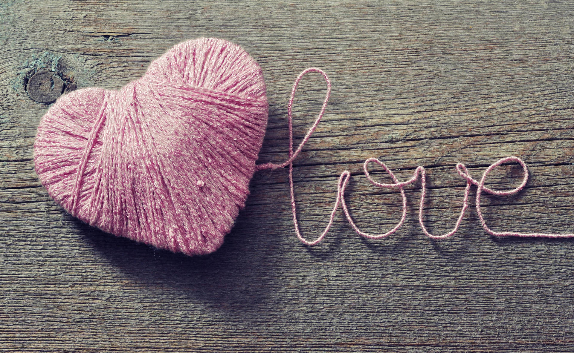 Từ 'Love' lãng mạn được viết bằng sợi dây màu hồng tạo hình trái tim trên bàn gỗ cho Ngày lễ Tình nhân.