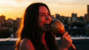 Vivo trình diễn một bài hát đầy cảm xúc trên sân thượng khi mặt trời lặn, tay cầm maraca.