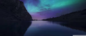 Cực quang Borealis siêu rộng với bầu trời xanh lam và tím pastel đầy sao, nhìn từ những ngọn núi.