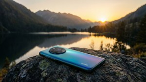 Điện thoại Huawei đặt trên tảng đá nhìn ra hồ núi lúc hoàng hôn, phong cảnh thanh bình.