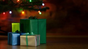 Những món quà đầy màu sắc xếp chồng dưới cây thông Noel với đèn lấp lánh. — Quà Giáng Sinh Hình nền
