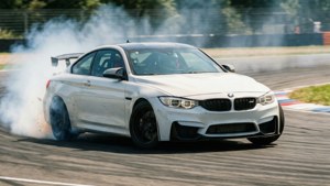 Một chiếc BMW M4 màu trắng đang drift qua khúc cua trên đường đua với khói bốc từ bánh xe và hiệu ứng mờ chuyển động. — Bmw Hình nền